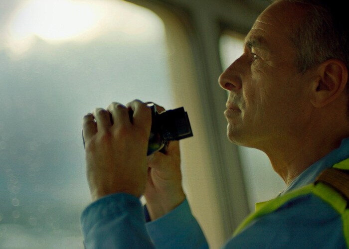 쌍안경으로 항구를 바라보는 책임자