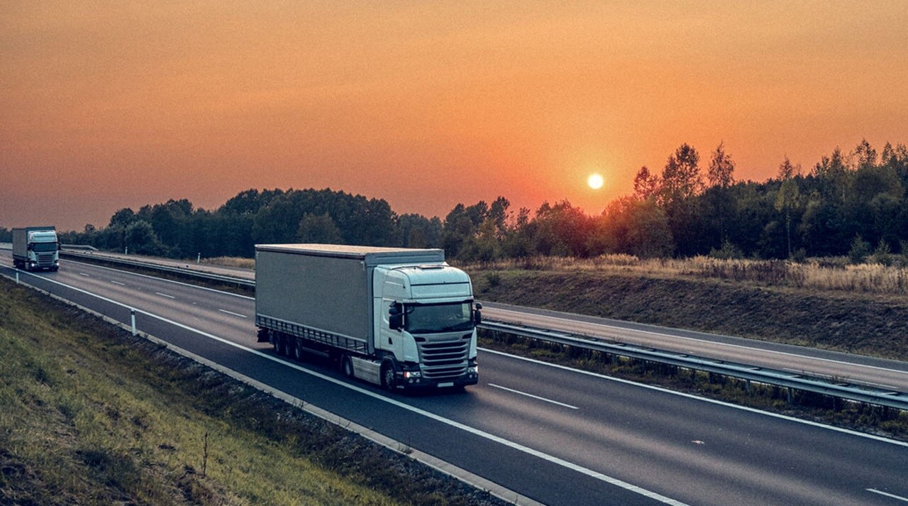 A truck drives along a highway at sunset.