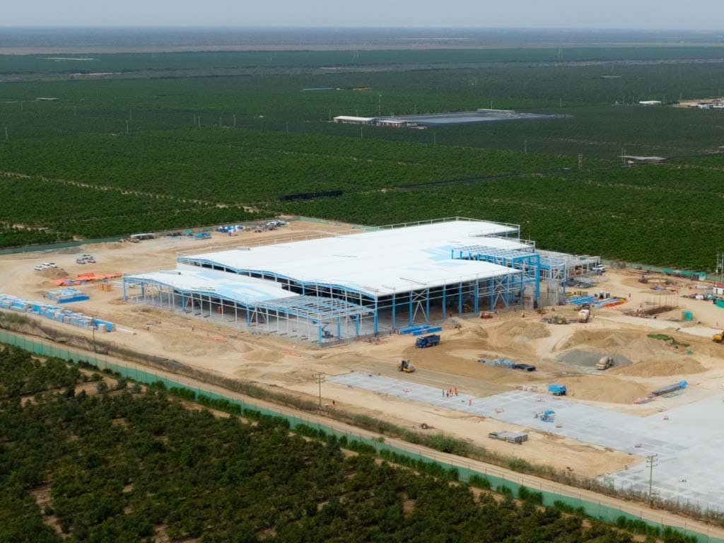 Aerial view of a large building under construction, showcasing scaffolding and construction equipment surrounding the site.