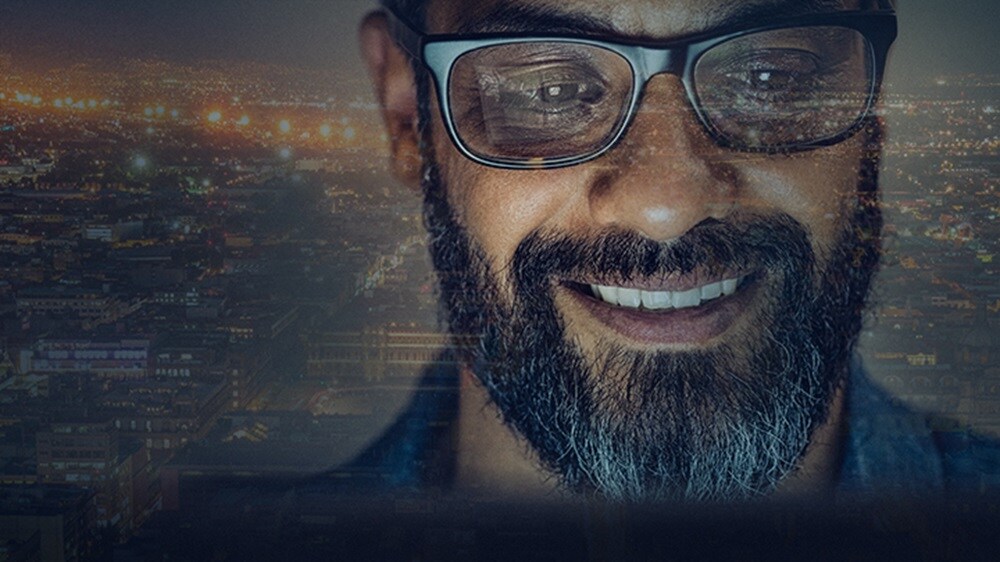 在馬士基的技術生涯- 一名面帶微笑的員工身处整個城市的夜色中。