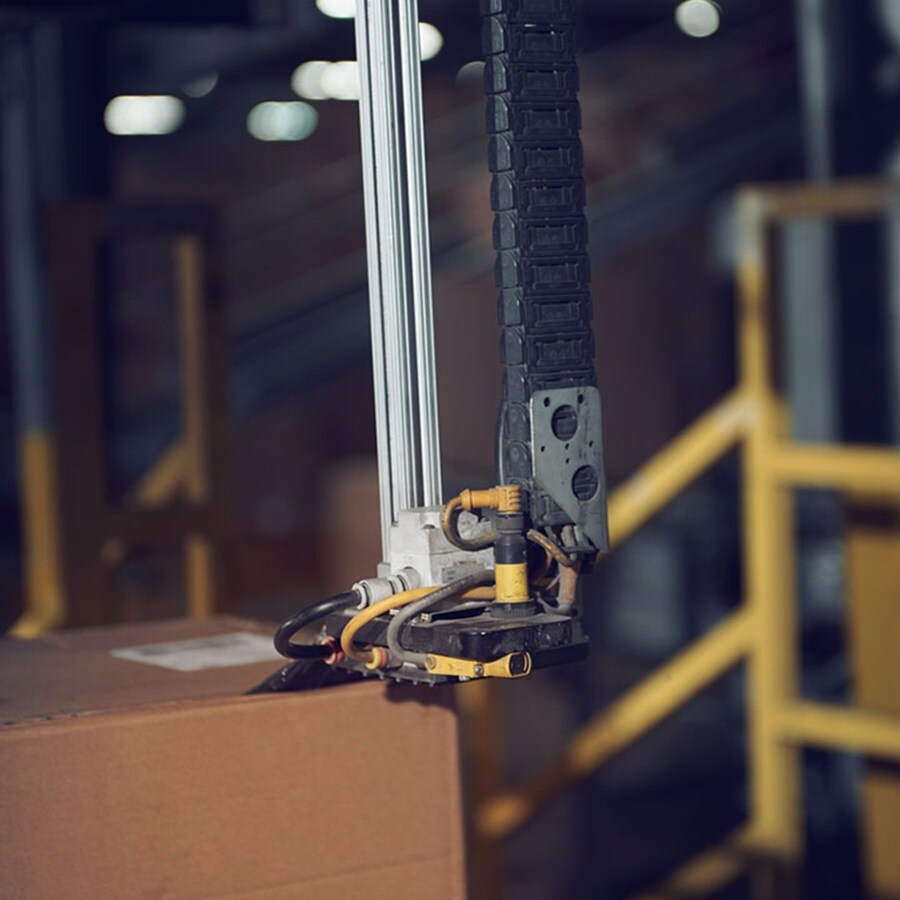 Brown cardboard boxes move along a conveyor belt in a warehouse