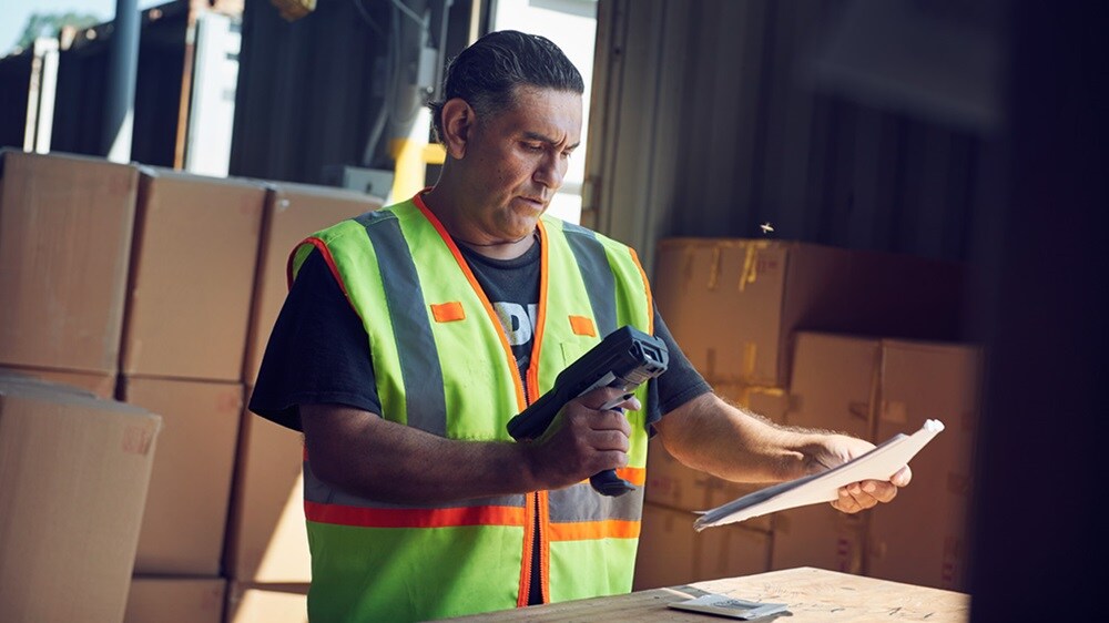 A logistics worker in a warehouse scanning trade documents