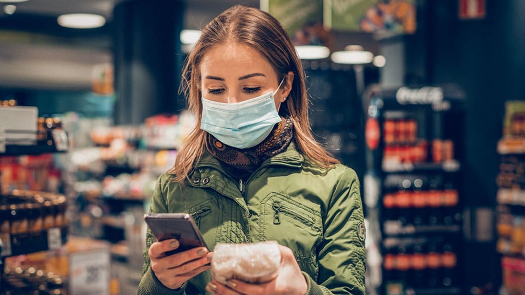 Woman in face mask checking product label at grocery store