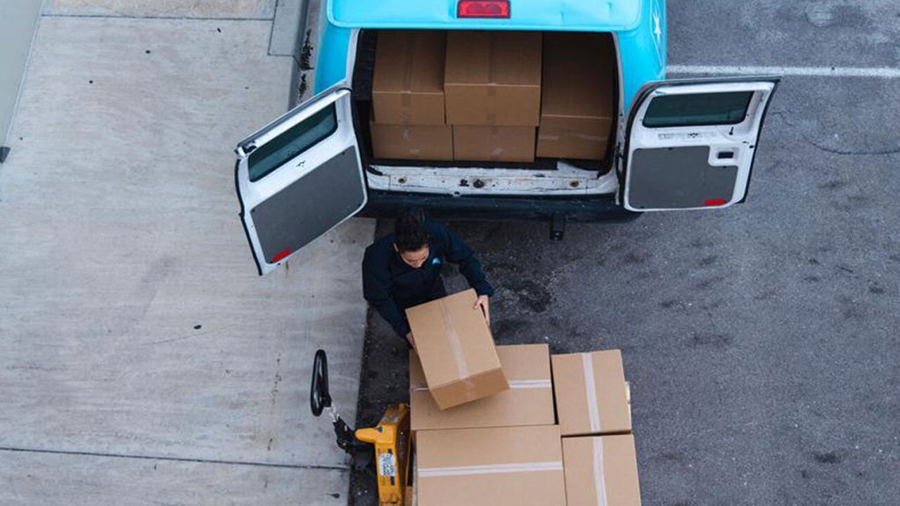 A woman unloads a delivery from a van showing how integrated logistics can help optimise speed to market.