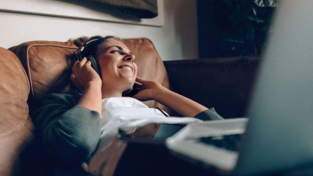 Speed to market matters to consumers like this woman lying on a couch with a laptop on her knees and listening to her headphones.
