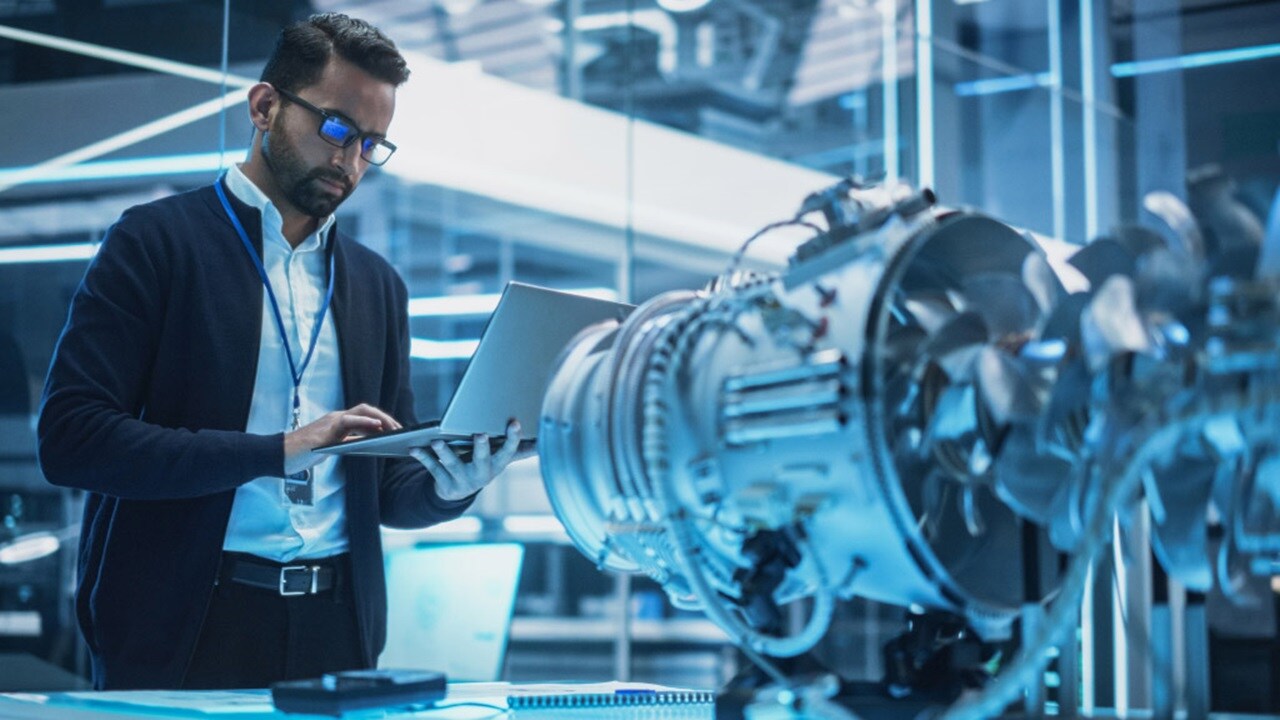 A man in a suit is focused on his laptop, working intently in a professional setting.