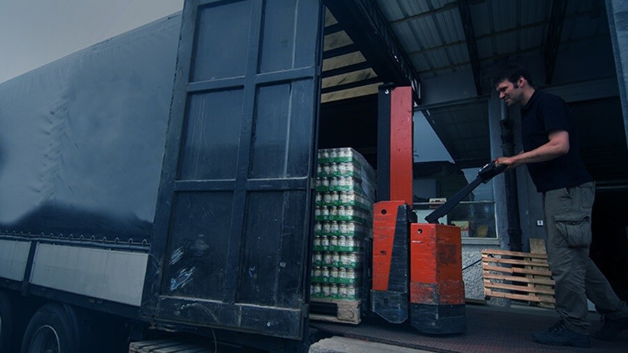A male worker loading fast moving consumer goods onto a truck.