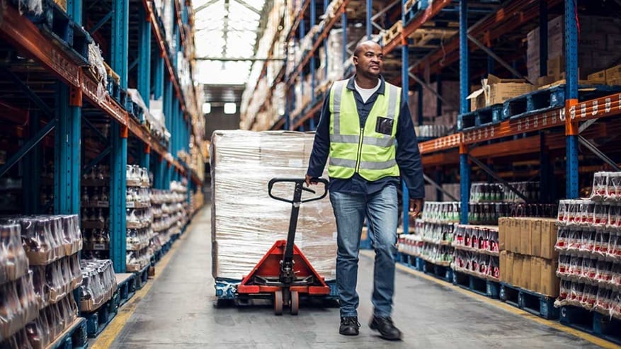 Man in warehouse wearing a yellow vest and moving products 