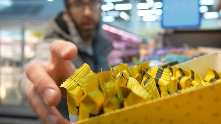 A customer reaches for a chocolate bar at a store display.
