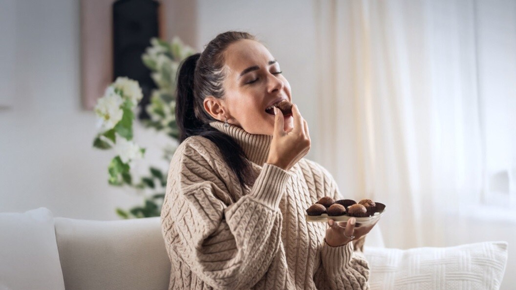 A woman enjoying chocolates on a cozy couch.