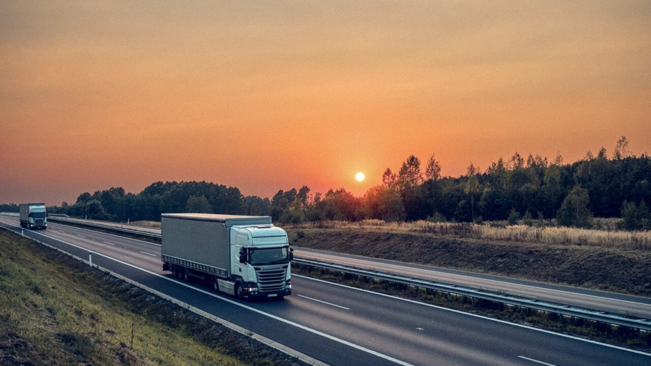 Truck driving on highway at sunset