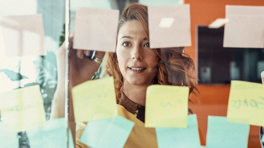 Female employee writing on a post-it attached to a glass window
