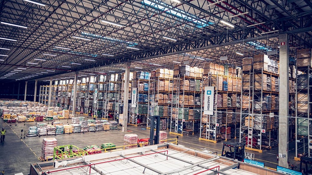 Interior view of a large Maersk-operated warehouse with high stacked pallets