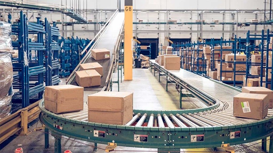 Cardboard boxes moving on conveyor belt in warehouse.