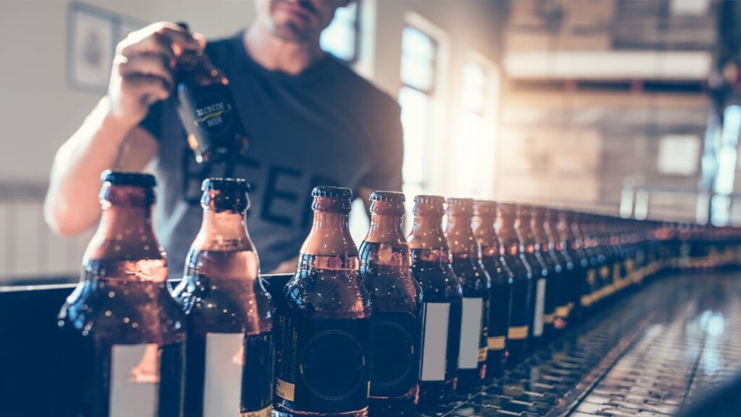 Man in grey t-shirt holding beer bottle