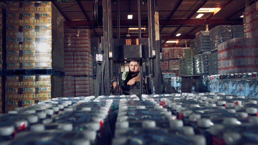 Worker at warehouse surrounded by bottles