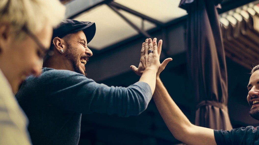 Two smiling men high five