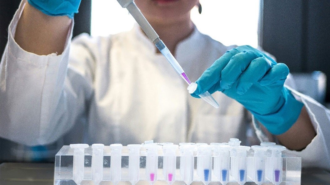 Female scientist pipetting colored chemicals into a tube