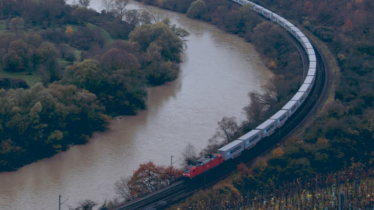 Birds eye shot of inland rail running along a river between the mountains