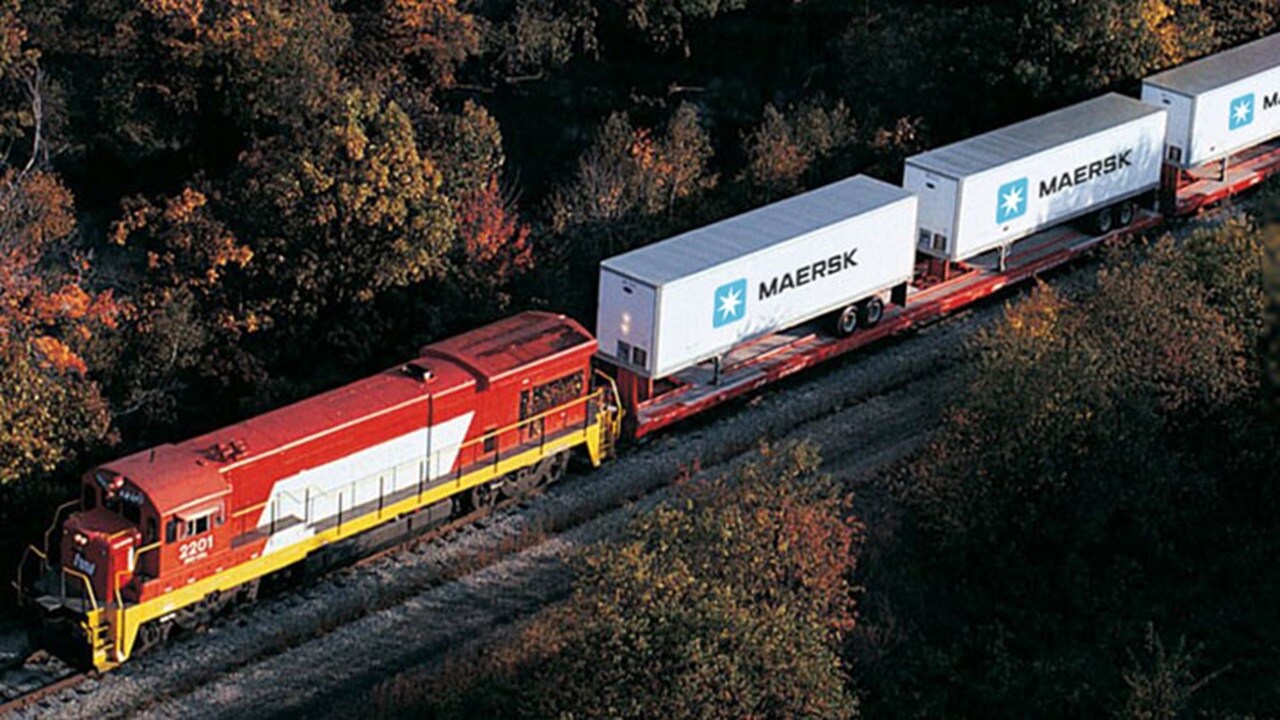 An aerial view of a train carrying Maersk containers with refrigerated cargo.