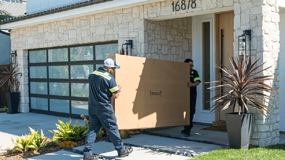 Two delivery workers carrying a large fragile package