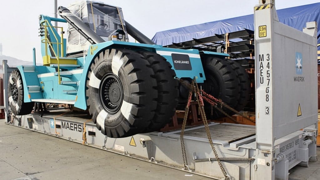 A large, heavy-duty piece of machinery, is secured on a flatbed container