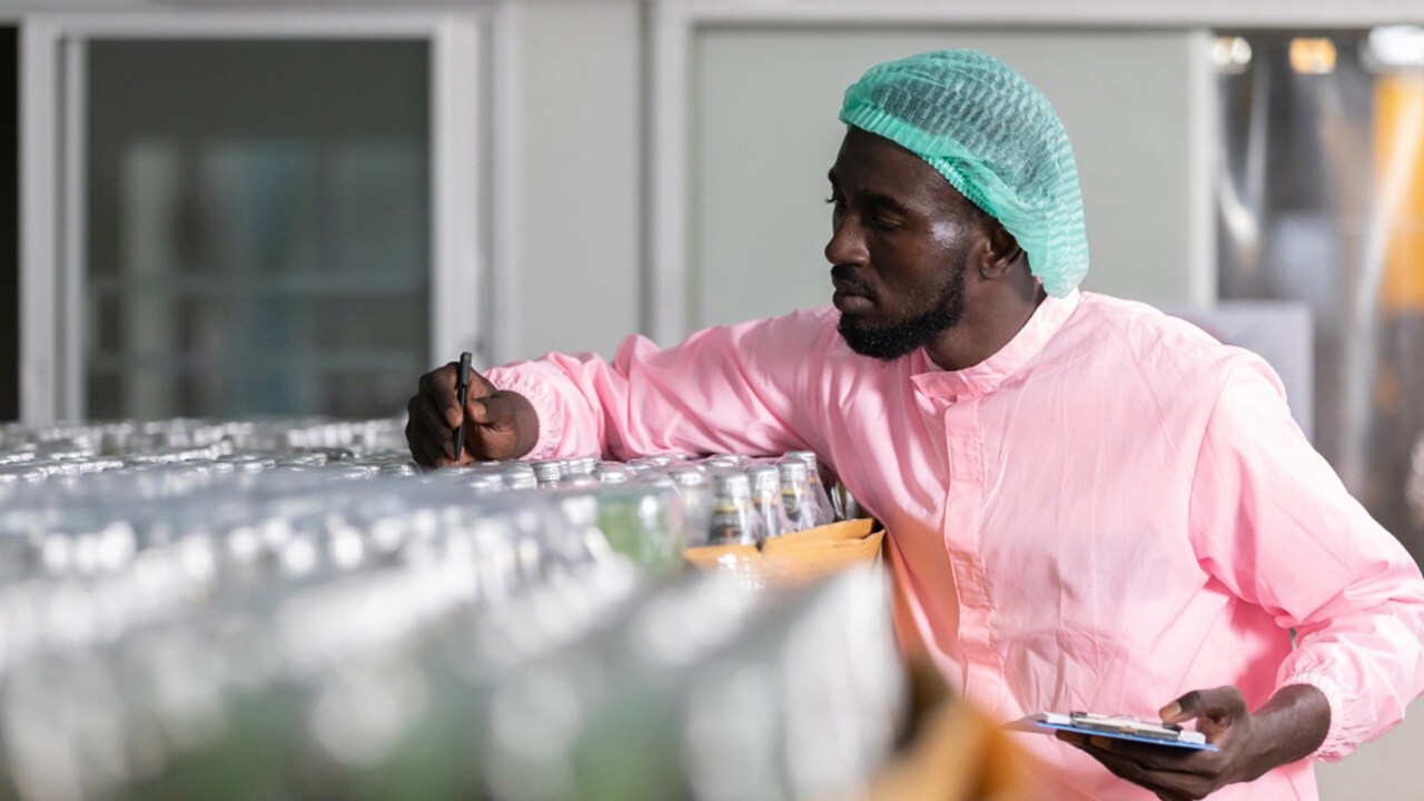 Worker inspecting bottles in a processing facility.