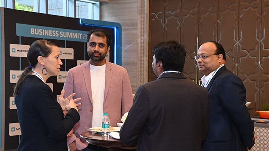 Business professionals networking at a summit in Mumbai, with a backdrop of modern conference facilities.