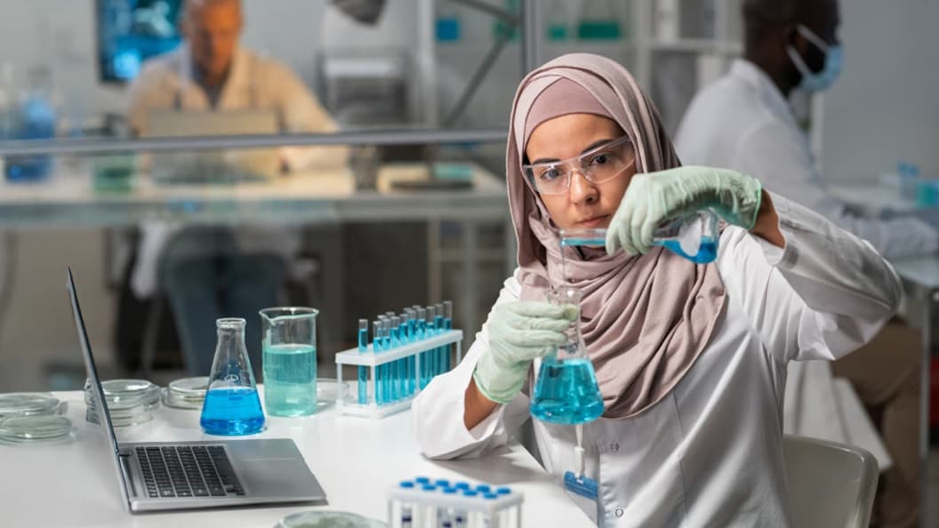 Scientist mixing blue liquid in lab flask.