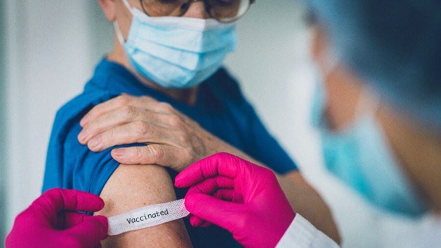 A vaccinated man, with 'vaccinated' sticker being placed on his arm