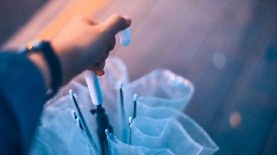 Hand holding an umbrella with white handle