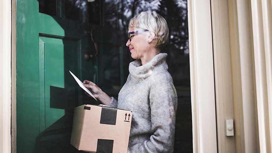 Woman receiving a parcel and looking at her phone