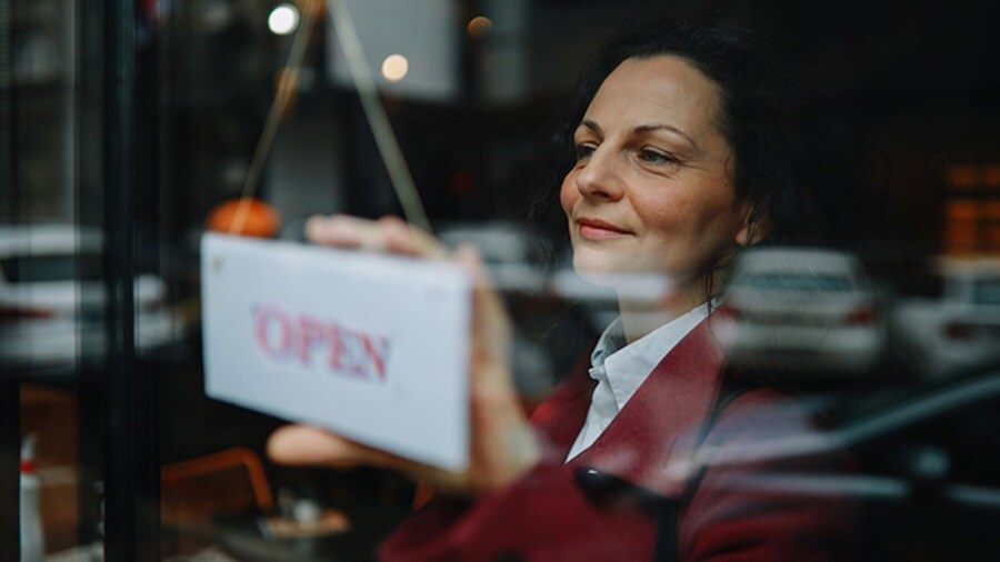 Woman holding a open sign on the store