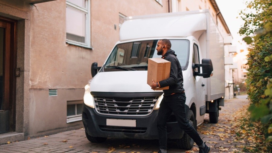 Male delivering a shipment with white truck in background