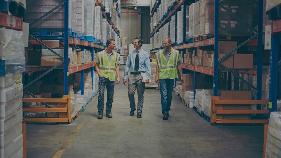 Three male conversing in a warehouse