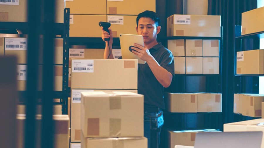 Male working in a warehouse scanning shipment boxes