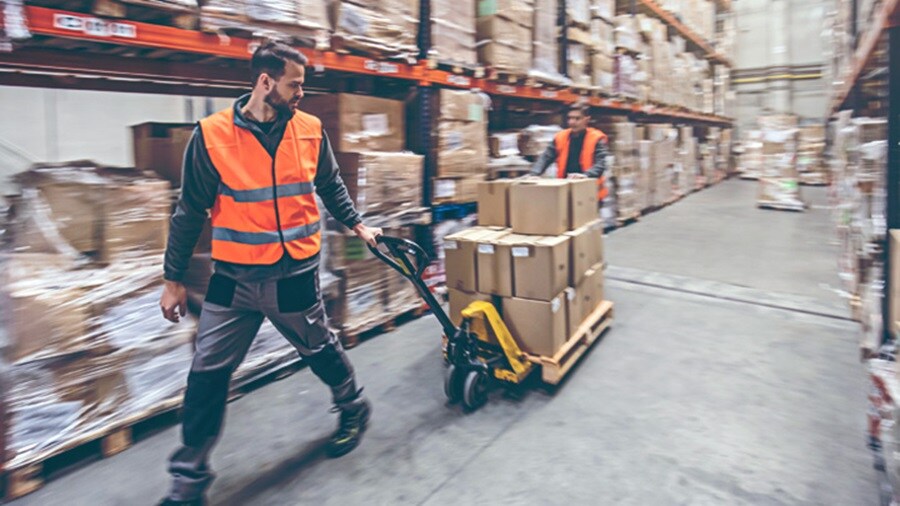 Man pulling a trolley of shipments in a warehouse