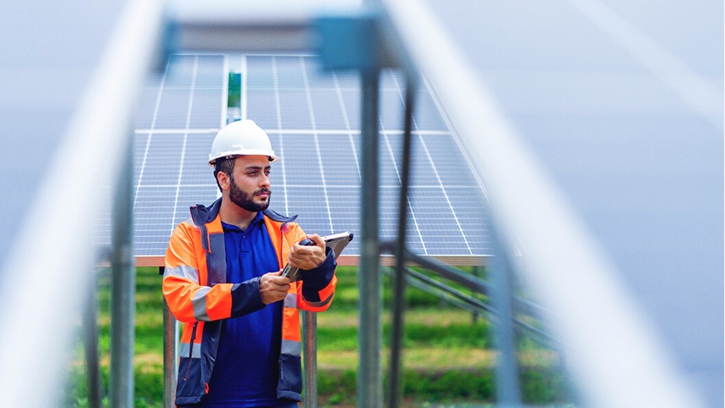 Male with protective gear standing between solar panels