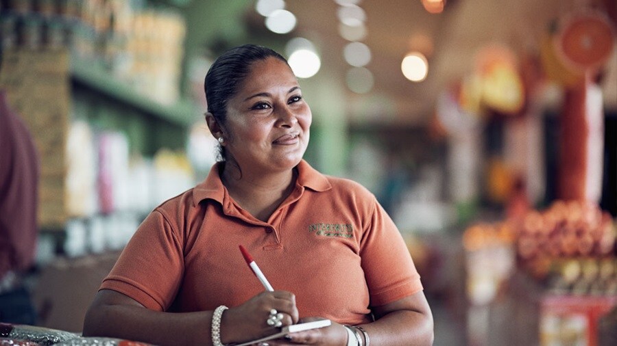 Mujer sonriente con bolígrafo y bloc de notas