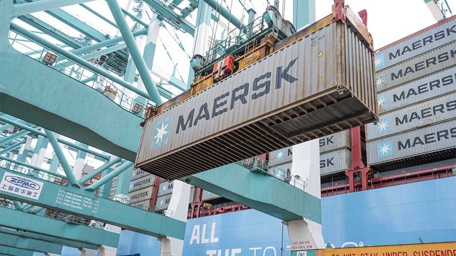Blue gantry crane lifting a MAERSK shipping container at a port.