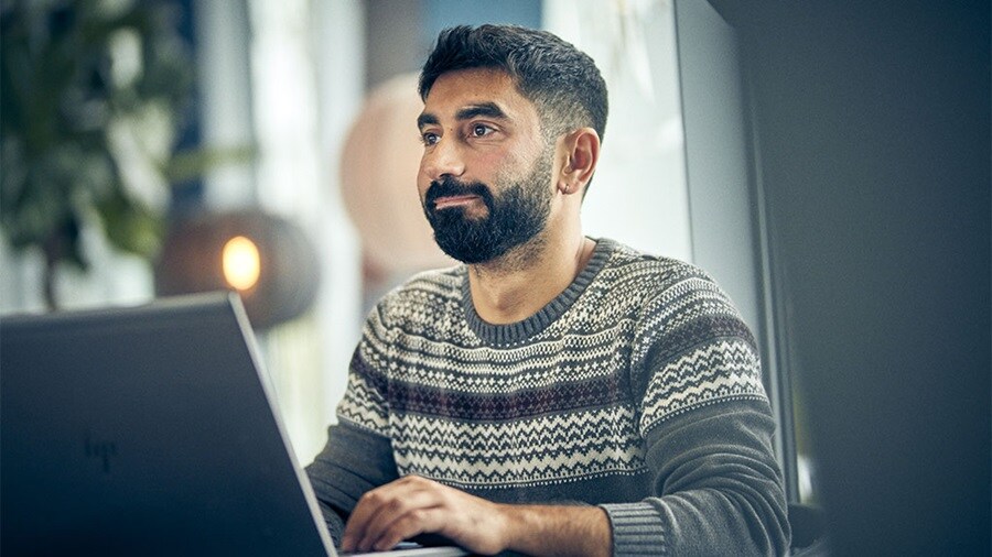 A male smiling in front of a laptop