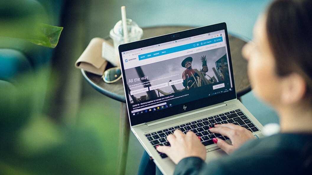 Woman typing on laptop. Looking at Maersk.com webpage.