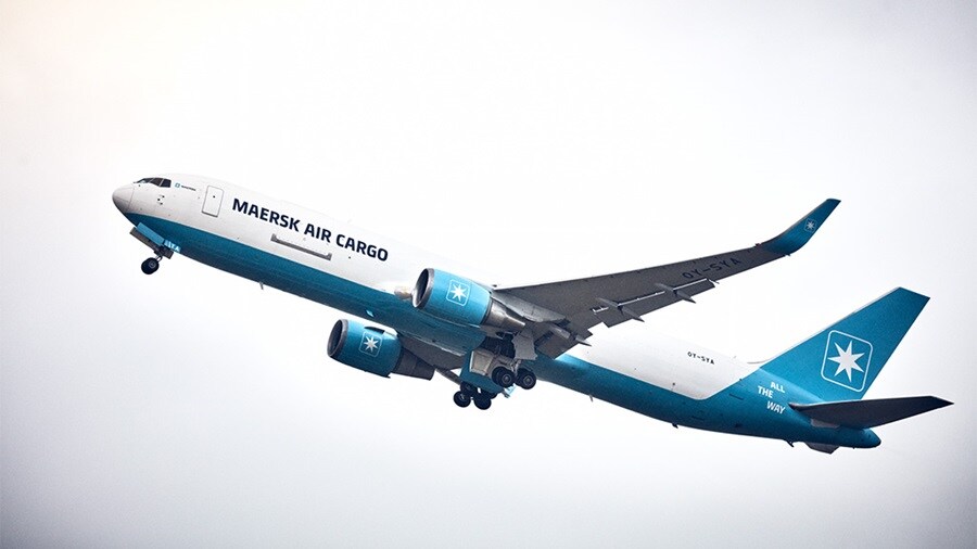 A Maersk Air Cargo plane taking off, showcasing its blue and white livery with the company logo on the fuselage and tail.