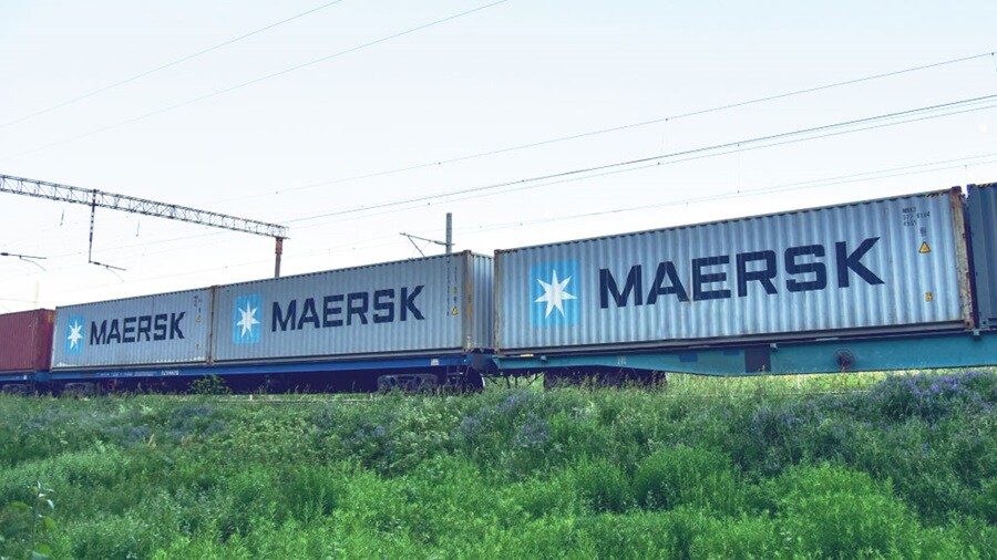 A Maersk freight train featuring a container car, showcasing its cargo transport capabilities on a railway track.