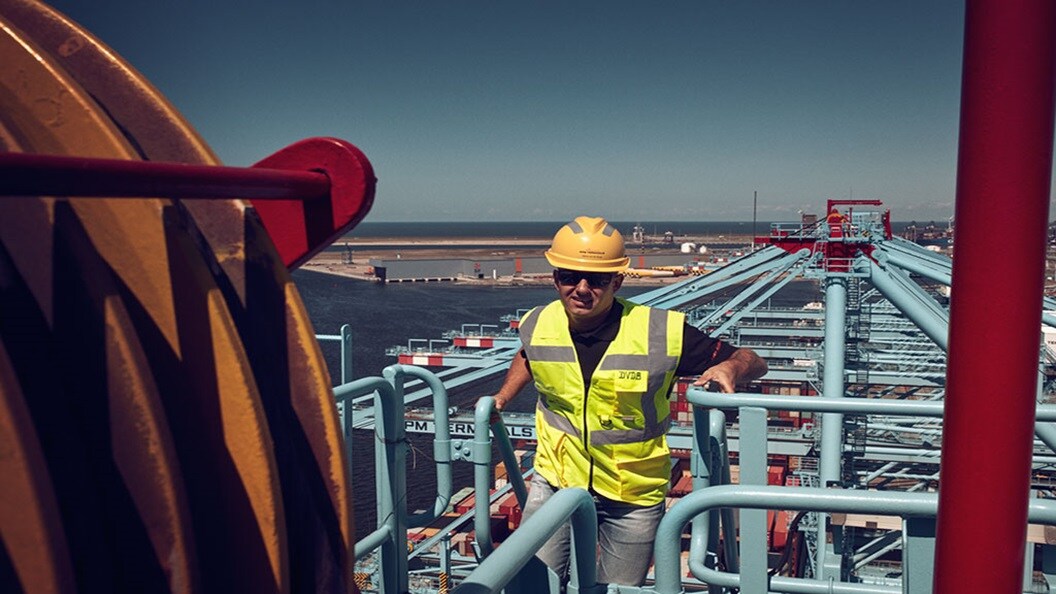 Crane operator standing on a crane with a view on the terminal.