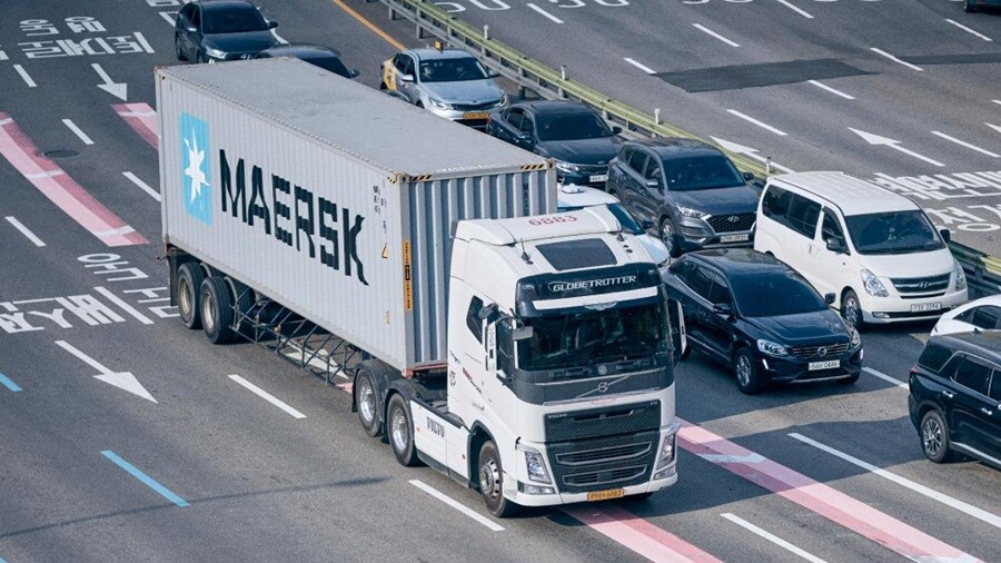 A truck navigates the road alongside multiple cars, illustrating a typical traffic situation.