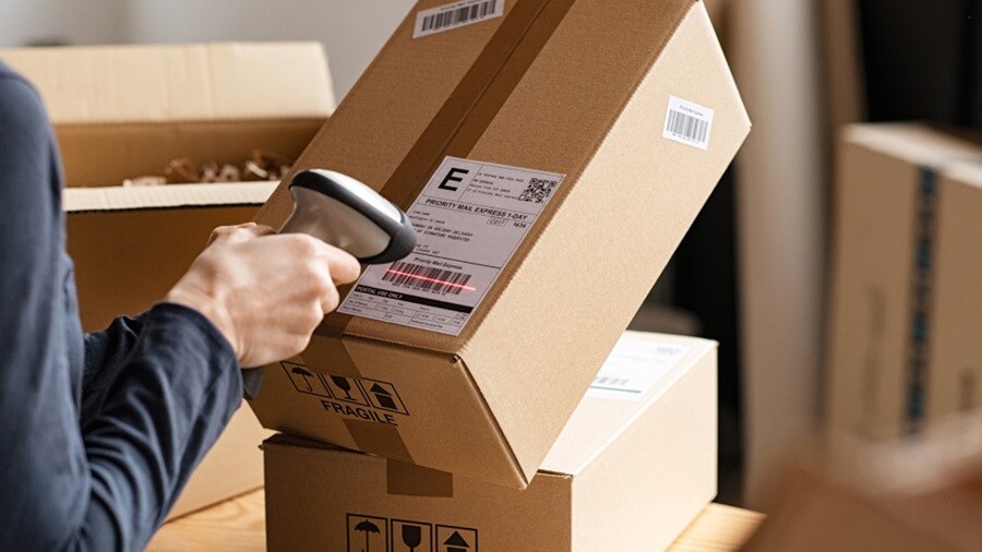 Person scanning a shipping label on a cardboard box.