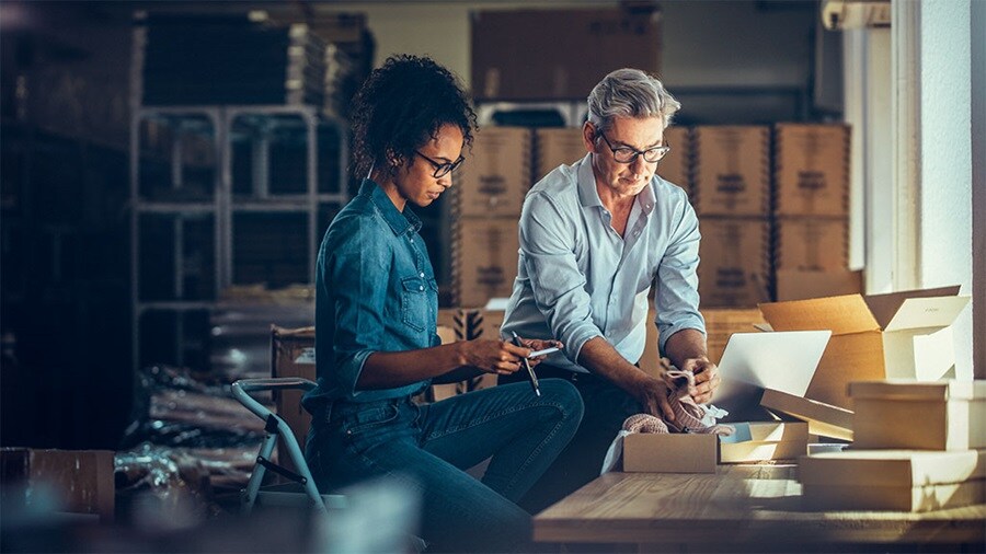 Two people packing products into boxes in a warehouse.