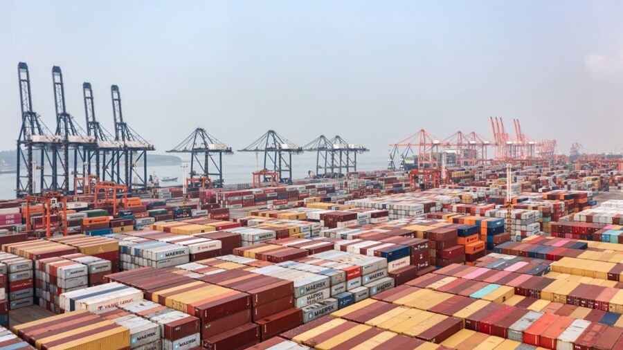 A large container port filled with numerous stacked shipping containers, showcasing a busy logistics hub.