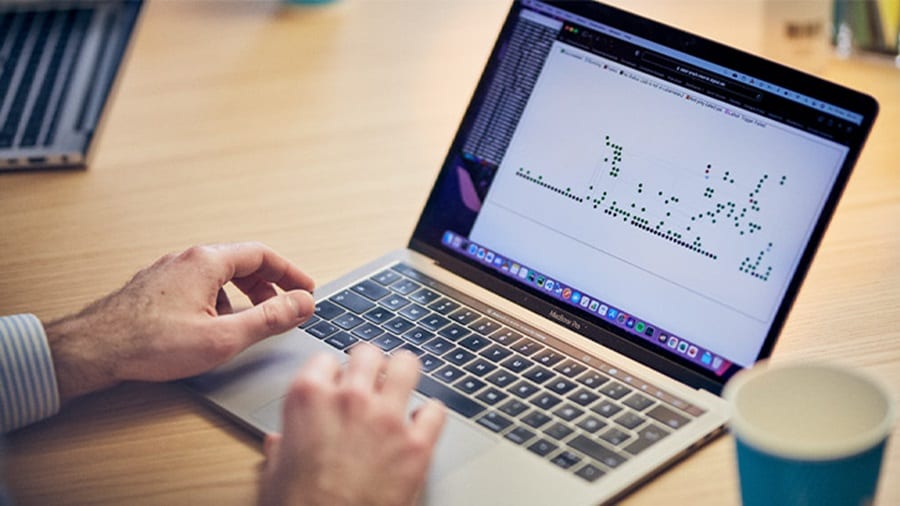 Person analyzing data on a laptop with a graph displayed on the screen.